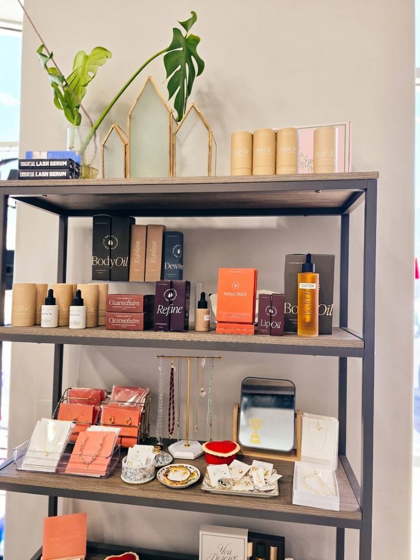 Shelves of body and lip oils, skincare, and delicate gold jewelry